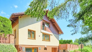 Una casa de dos pisos con techo inclinado, fachada de madera y un pequeño porche frontal.