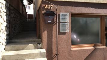 Um edifício com parede de pedra e escadaria de madeira que leva a uma porta com o número 247.