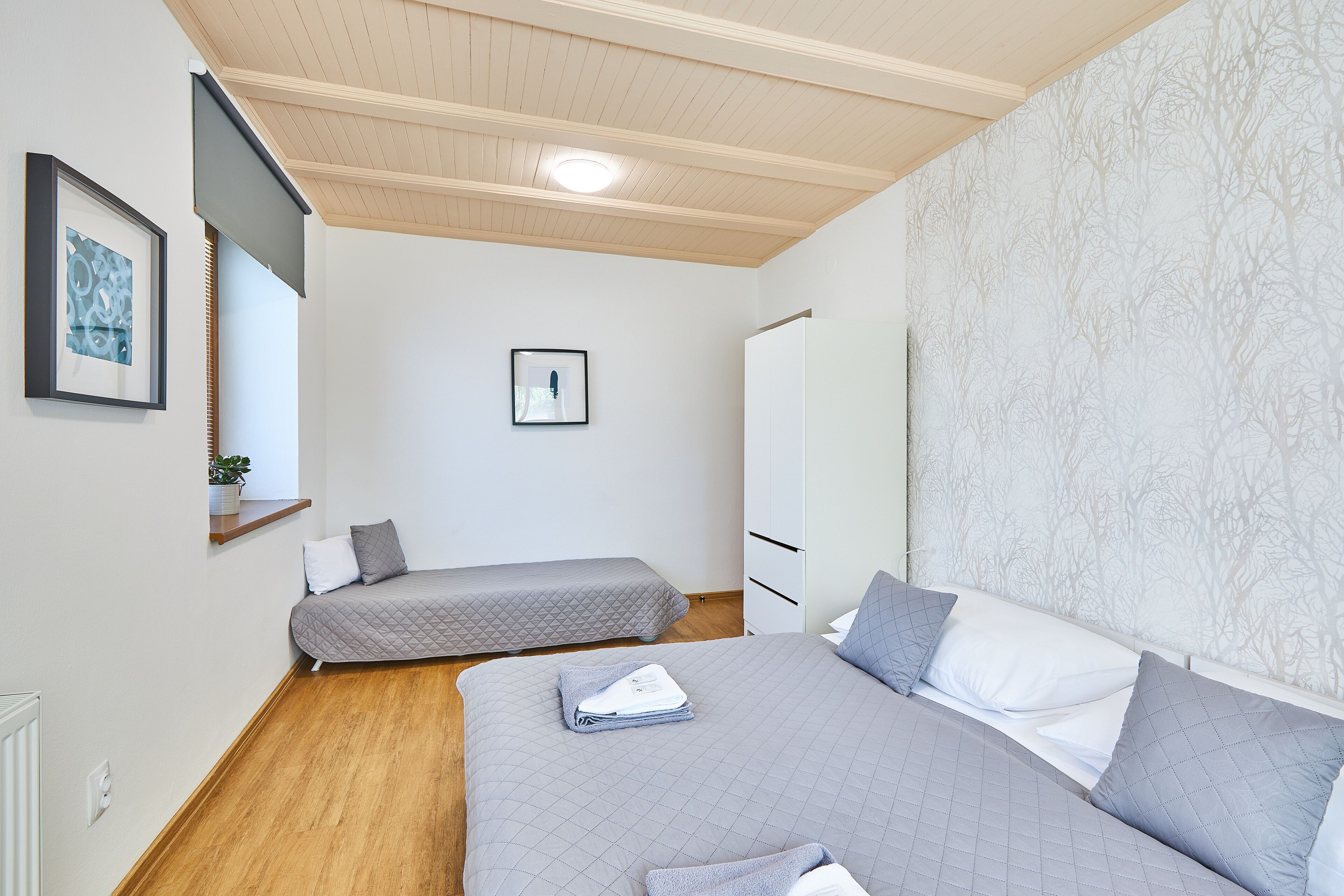 Una camera da letto con due letti, un armadio, un comodino e un quadro appeso al muro.