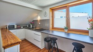 Una cocina moderna con armarios blancos, encimera de madera, microondas y ventana con vistas a edificios.