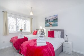 A hotel room with two beds, a large window, a painting, and a bedside table. - Shirley House (Gravesend)