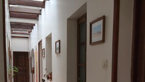 Un pasillo con vigas de madera, suelo de baldosas y plantas en macetas.