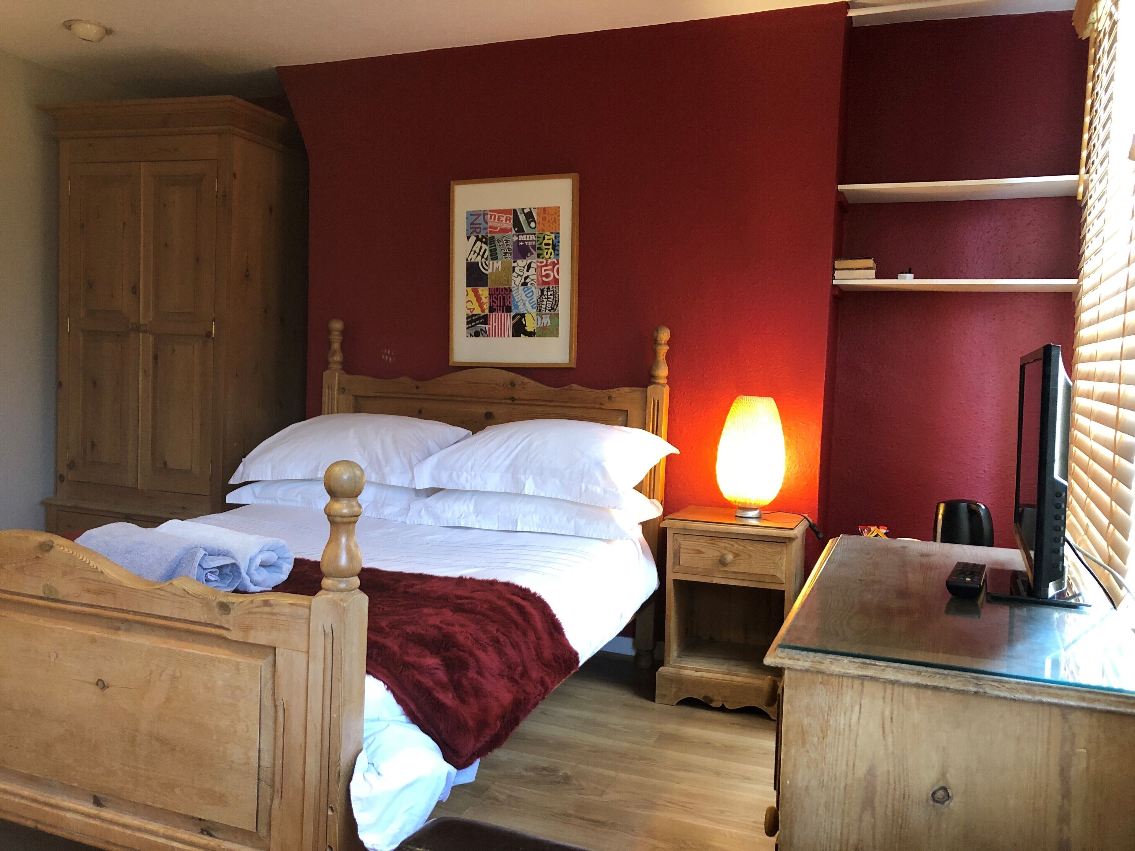 Une chambre à coucher avec un lit en bois, une table de chevet avec une lampe, une télévision et une armoire.
