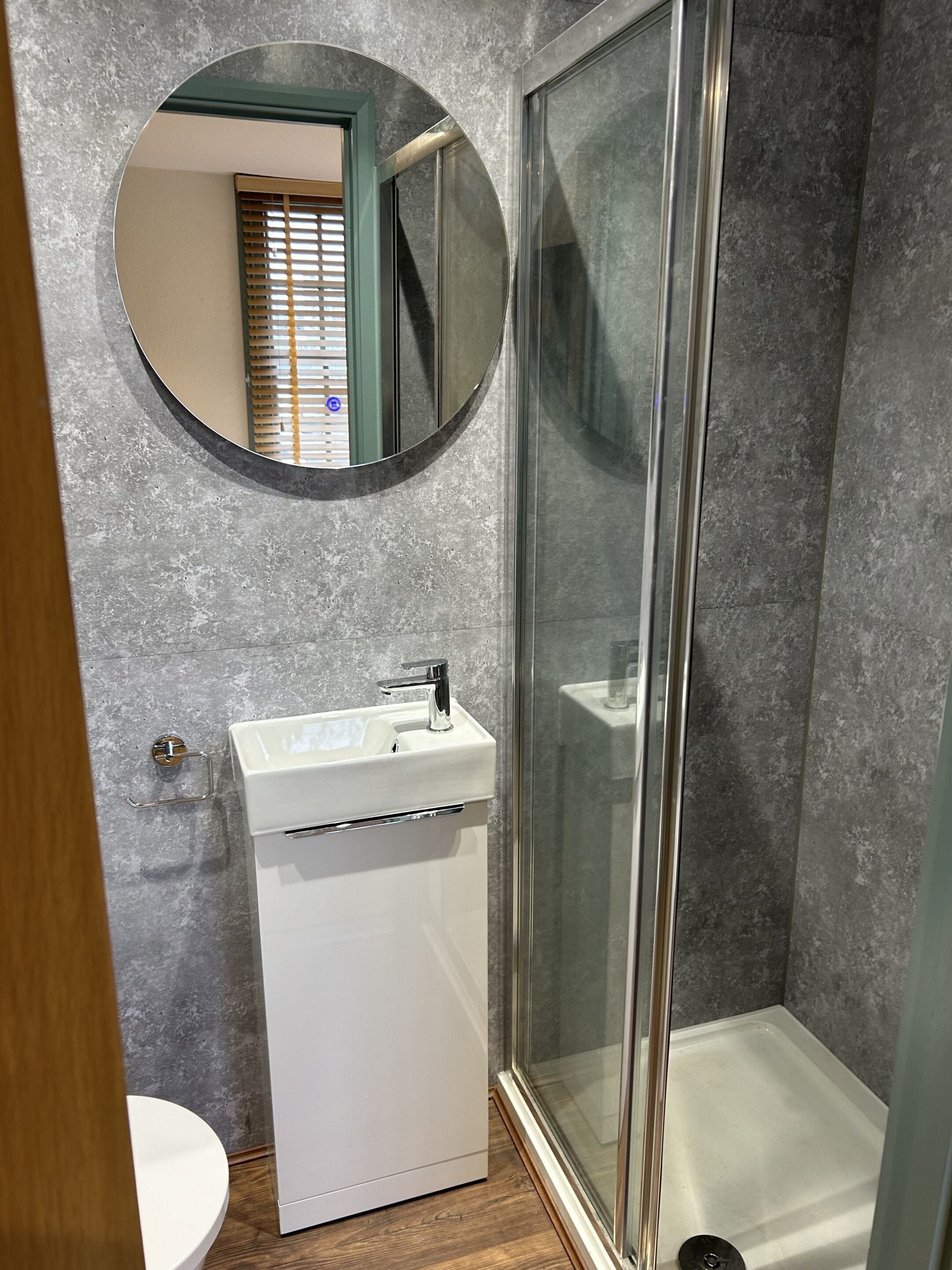 A bathroom with a white sink, a mirror, and a glass-enclosed shower.