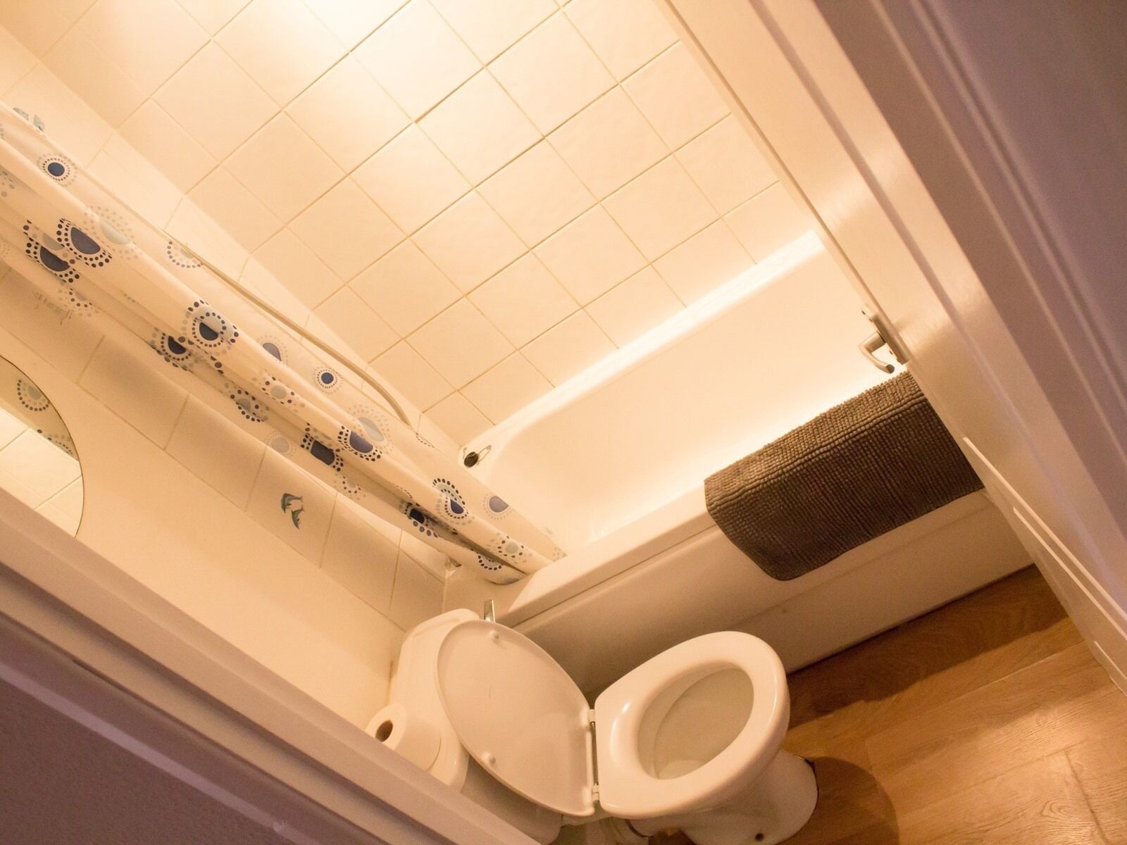 Un baño con bañera, dos inodoros y una cortina de ducha estampada.