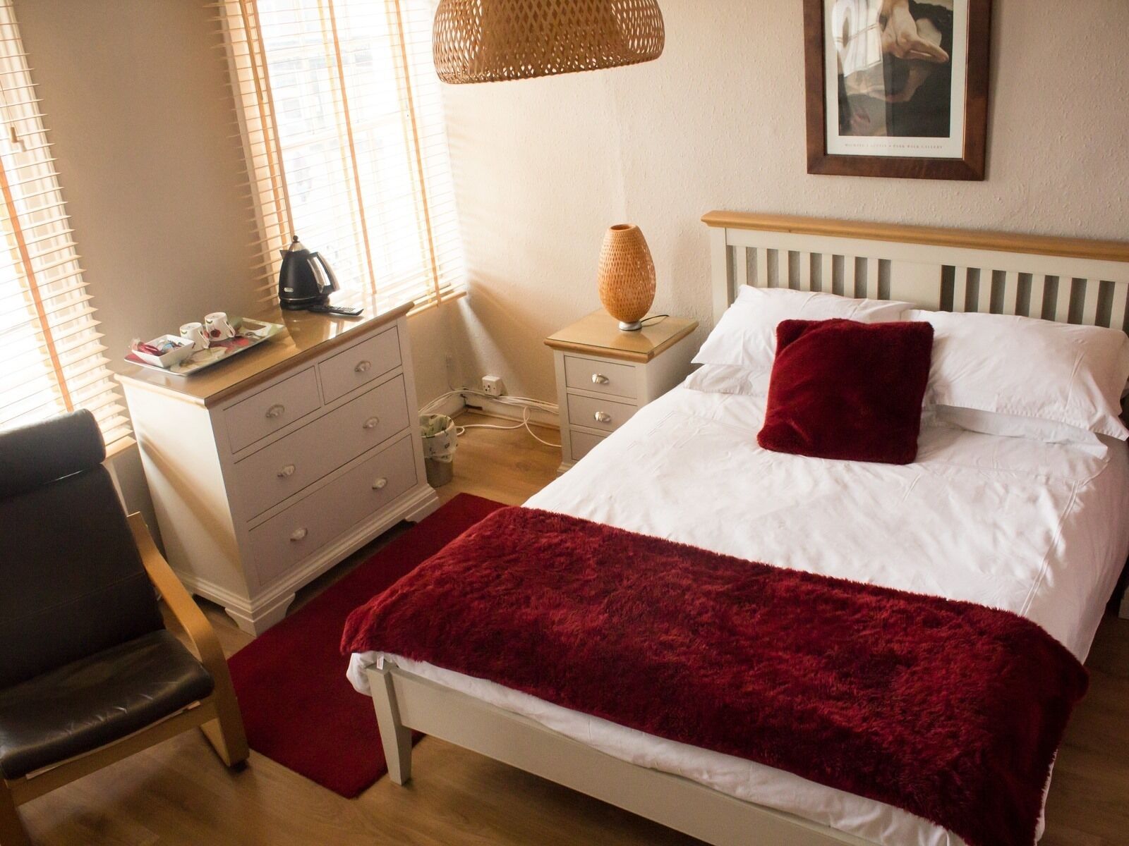 A neatly arranged bedroom with a bed, bedside table, lamp, and a chair.