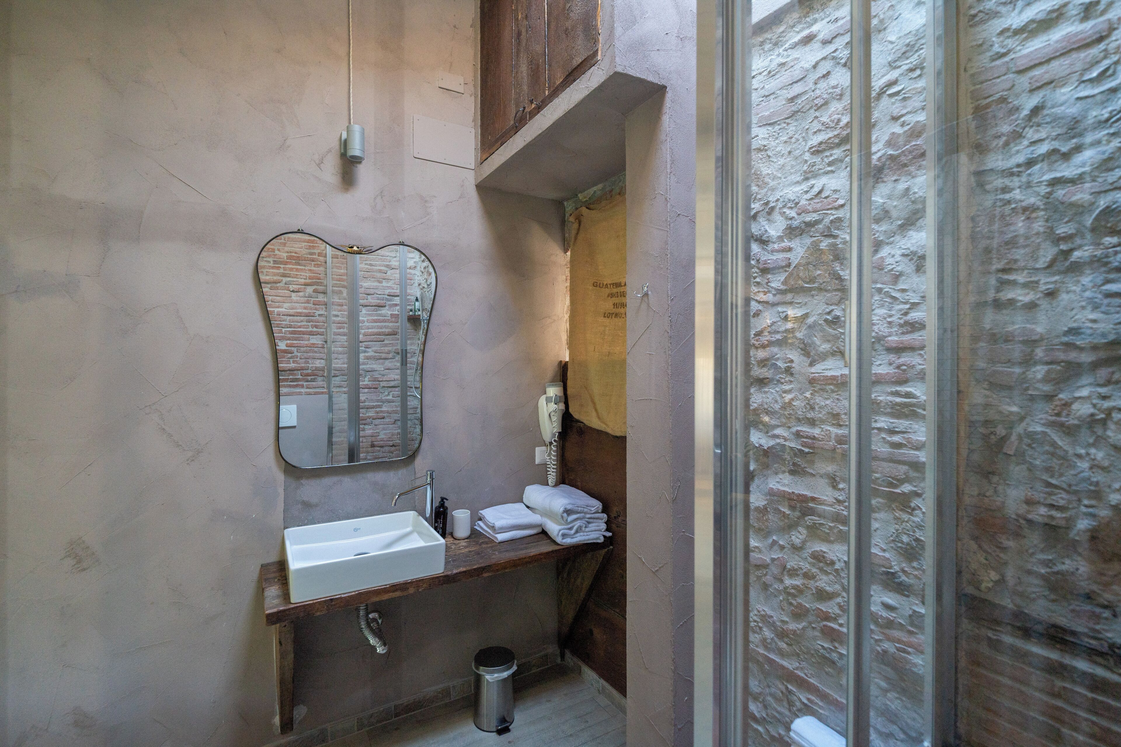 A bathroom with a sink, mirror, towel rack, and shower area.