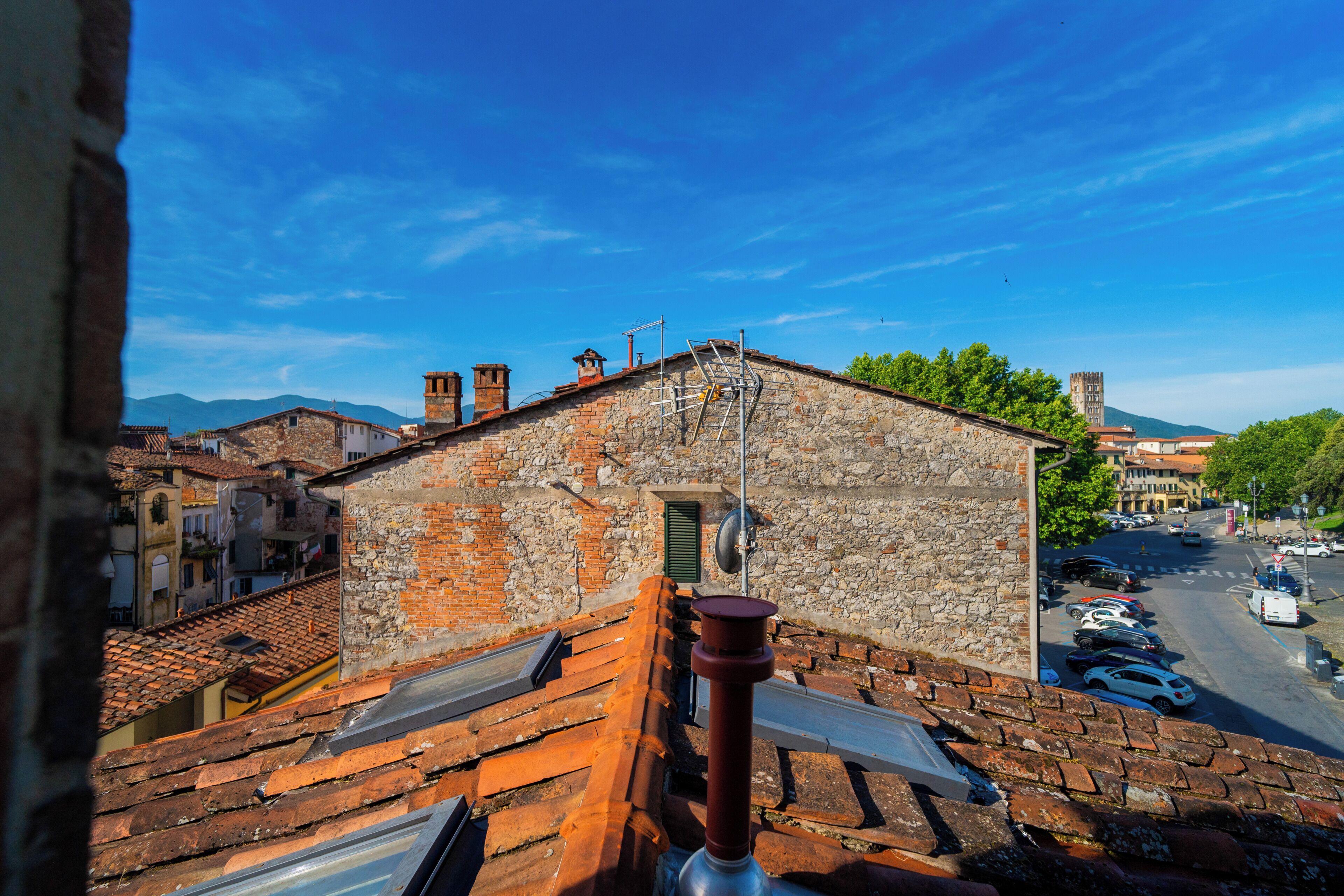 A stone building with a sloped roof, a chimney, and a metal antenna.