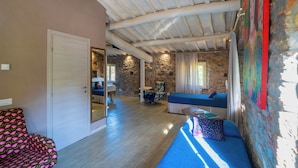 Una habitación con pared de piedra, techo de madera, un sofá, una silla y una cama.