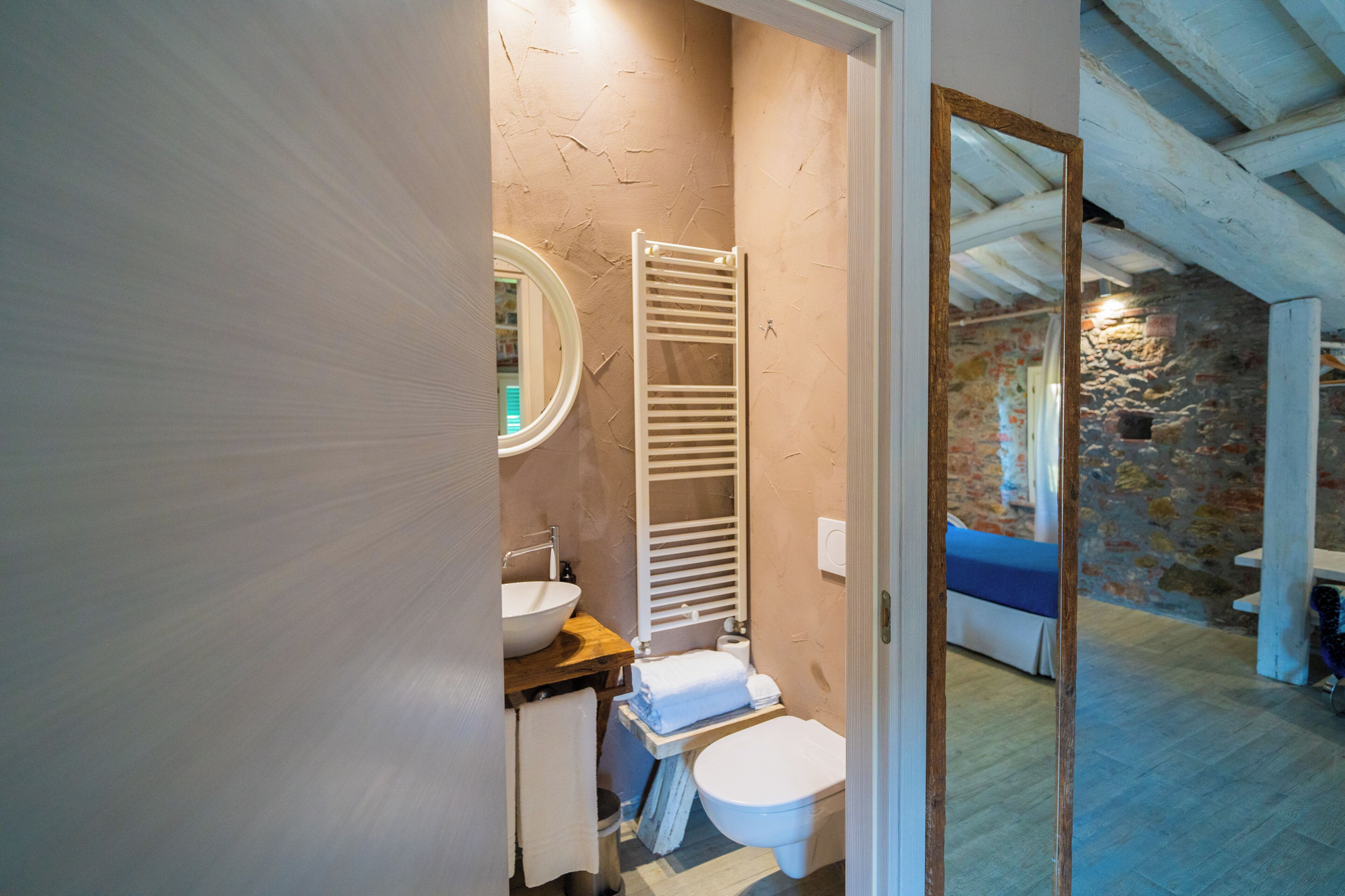 Et badeværelse med en hvid vask, et håndklædestativ, et toilet og et spejl.