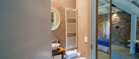 A bathroom with a white sink, a towel rack, a toilet, and a mirror.