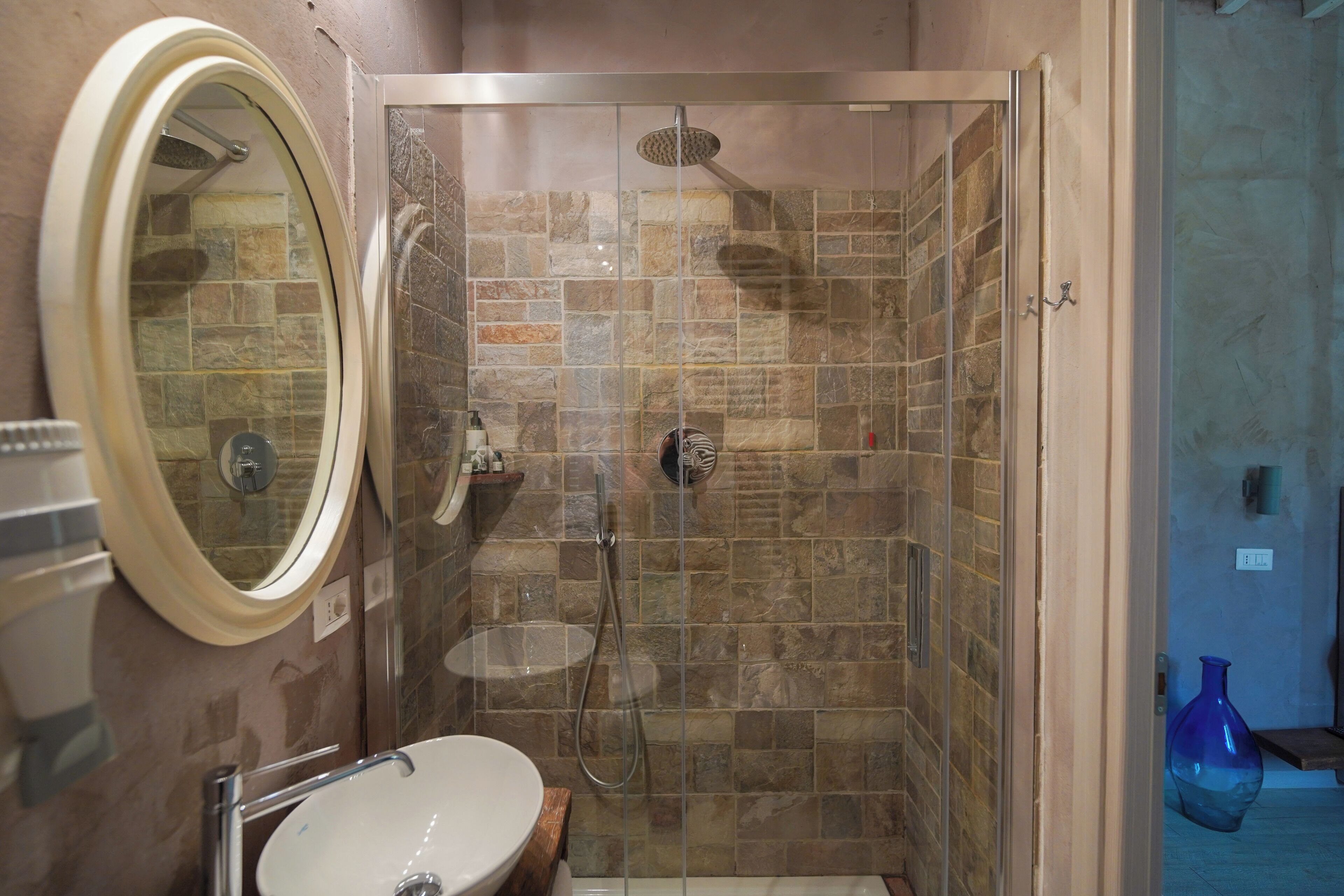 Ein Badezimmer mit Dusche, Waschbecken und Spiegel.