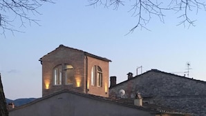 Un edificio con techo plano, varias ventanas con contraventanas y una antena parabólica.