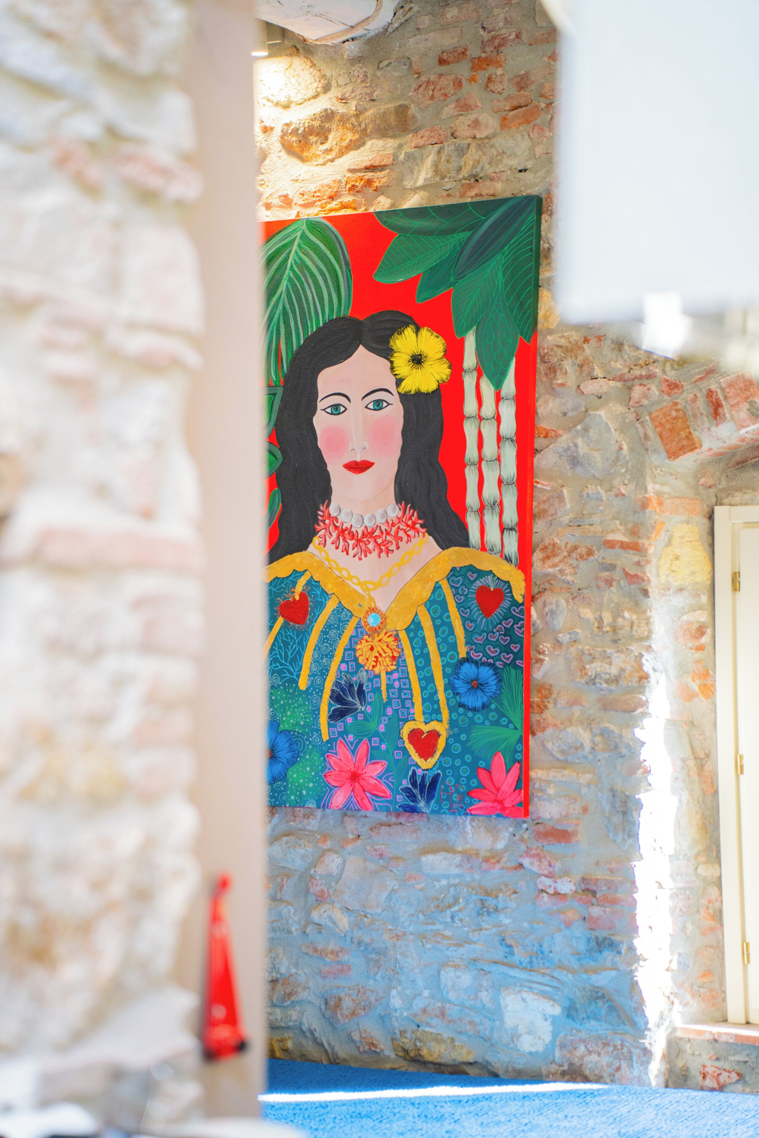 A mural with a woman in traditional attire, a stone wall, and a door.