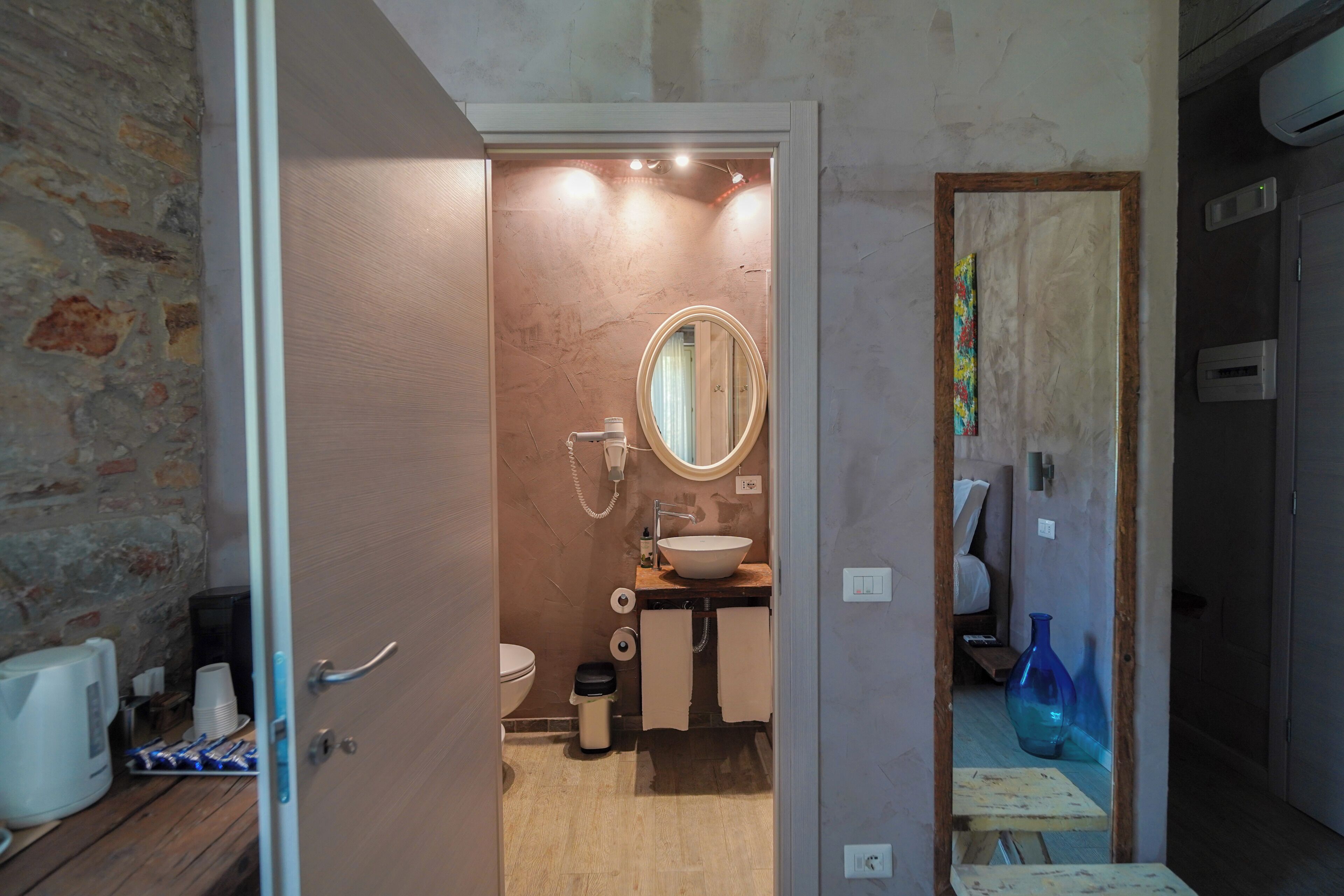 A bathroom with a wooden vanity, a round mirror, a toilet, and a sink.