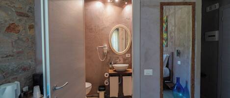 A bathroom with a wooden vanity, a round mirror, a toilet, and a sink.