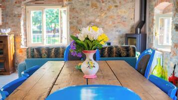 Une pièce rustique avec des murs en pierre, une table en bois et des chaises recouvertes d’un tissu bleu.