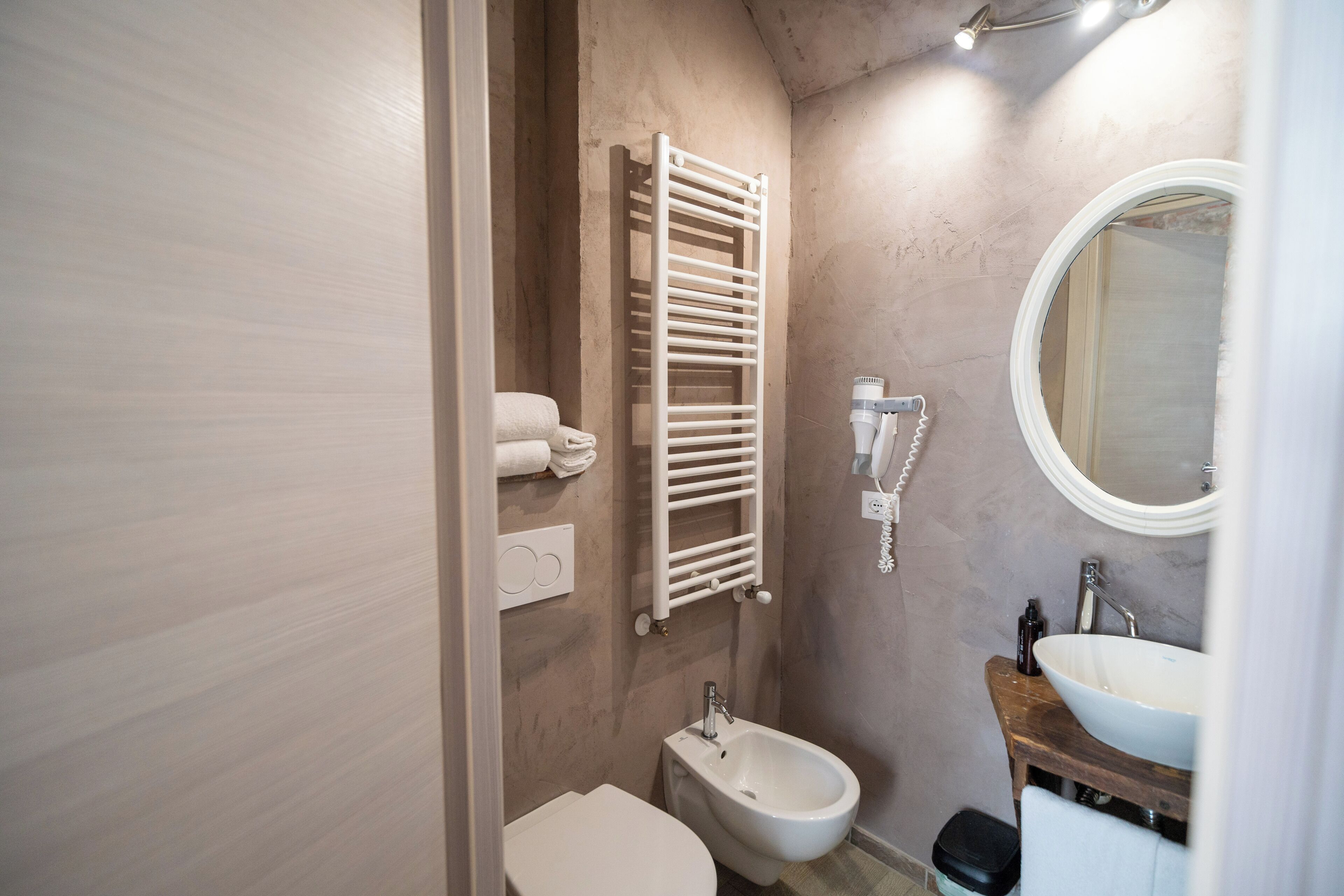 Een badkamer met toilet, bidet, handdoekhouder, wastafel en spiegel.