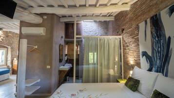 Ein Schlafzimmer mit Bett, einer Pendelleuchte, einem Fenster und einer Ziegelwand.