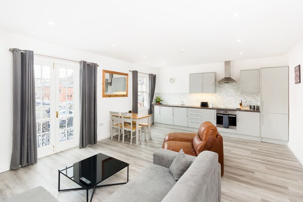 A modern apartment with a living room, dining area, and kitchen.