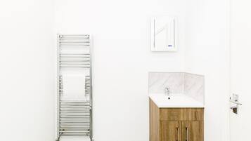A bathroom with a towel rack, a mirror, and a wooden cabinet with a sink.