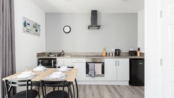 Eine moderne Küche mit Essbereich, ausgestattet mit Herd, Backofen, Mikrowelle und Geschirrspüler.