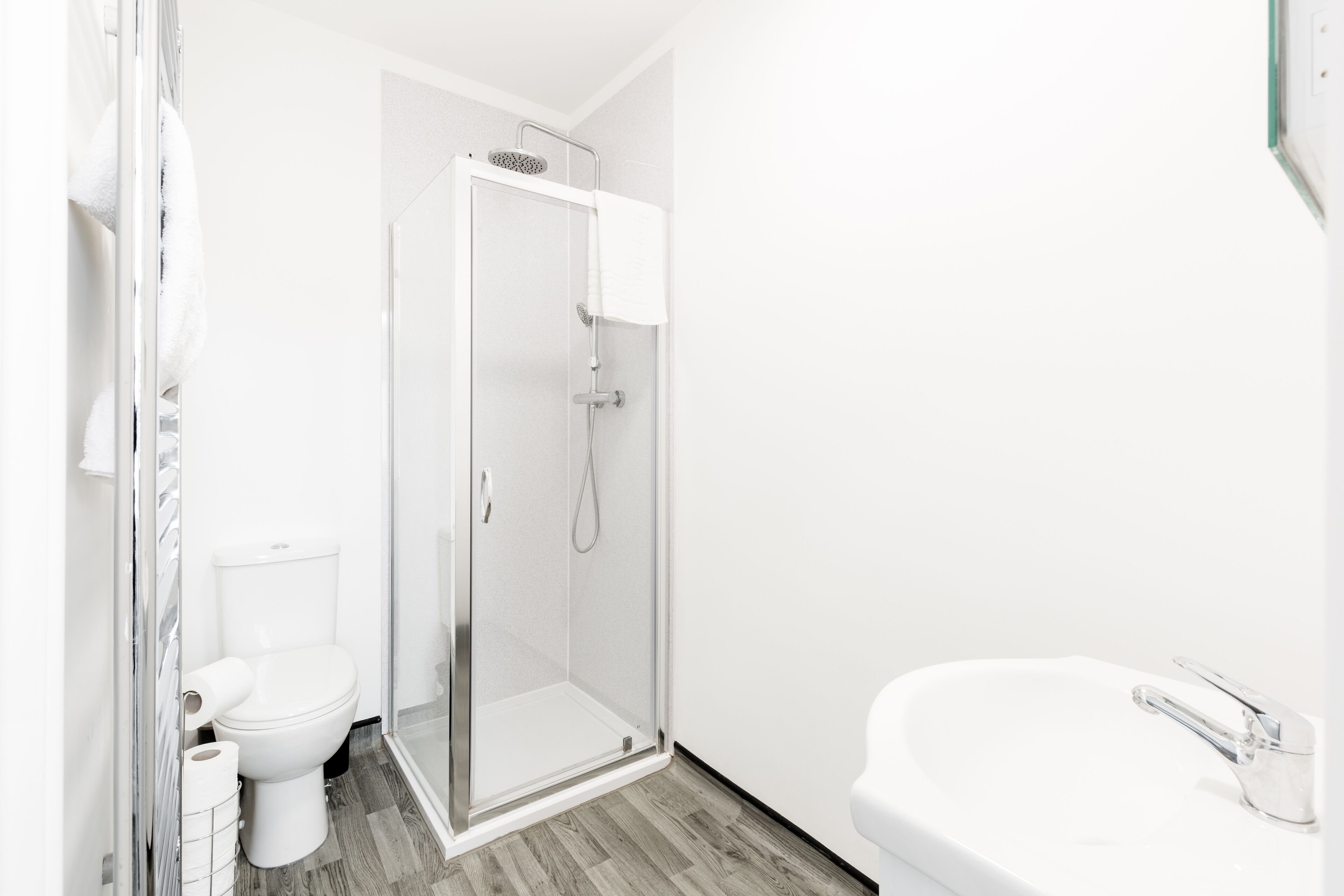 A modern bathroom with a toilet, shower, and sink.