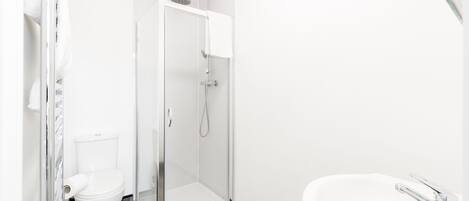 A modern bathroom with a toilet, shower, and sink.