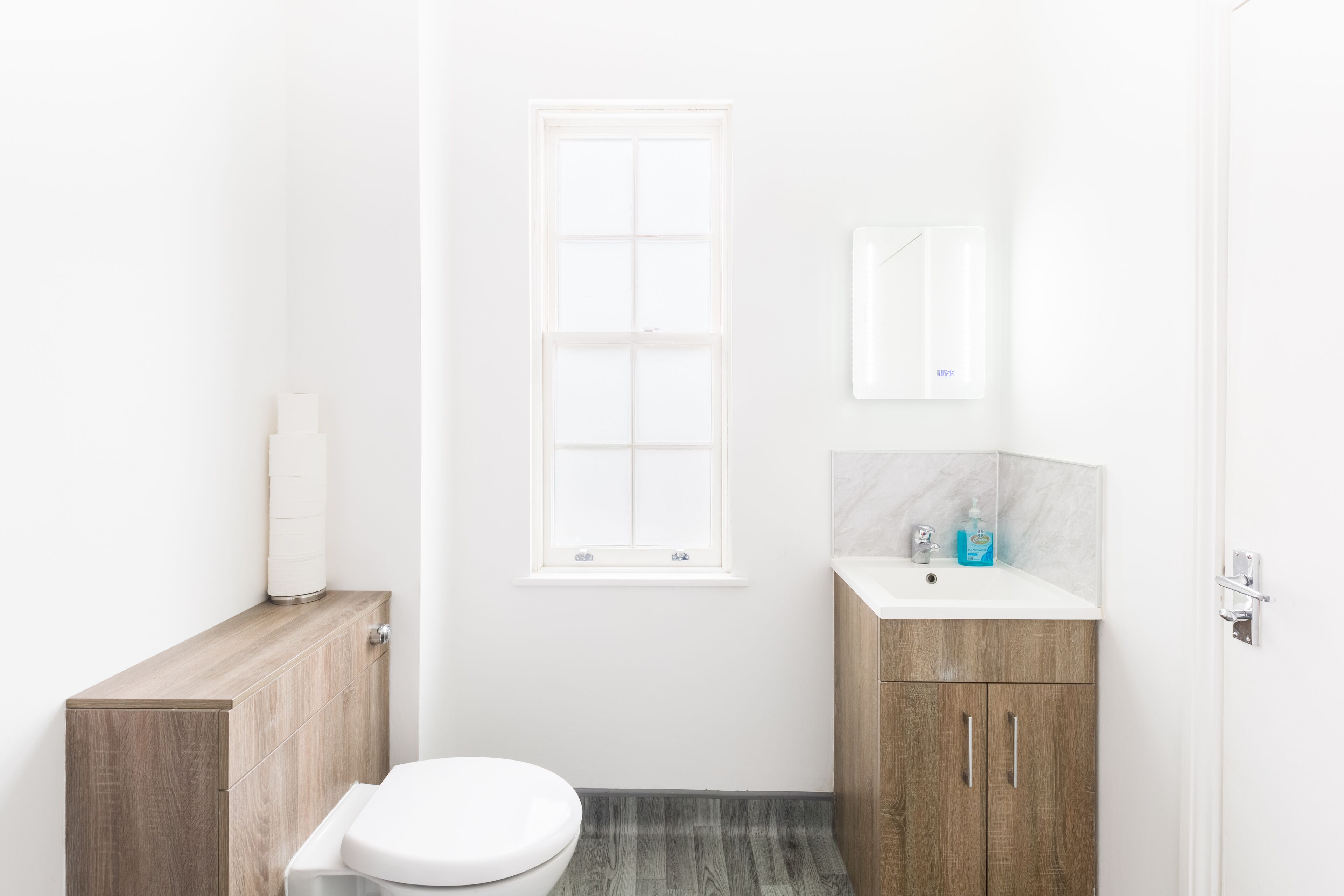Un bagno moderno con il water, un mobiletto in legno e un lavabo con schienale in marmo.