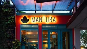 Un edificio con un letrero que dice "MANTURA" y un símbolo de loto sobre la entrada.
