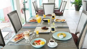 Una mesa de desayuno servida con diferentes platos, bebidas y una taza de café.