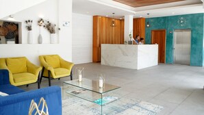 Un vestíbulo moderno con una mesa de recepción, sillas amarillas, una mesa de centro de vidrio y un techo de madera.