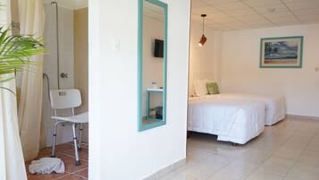 A hotel room with a shower, a bed, a chair, and a mirror.
