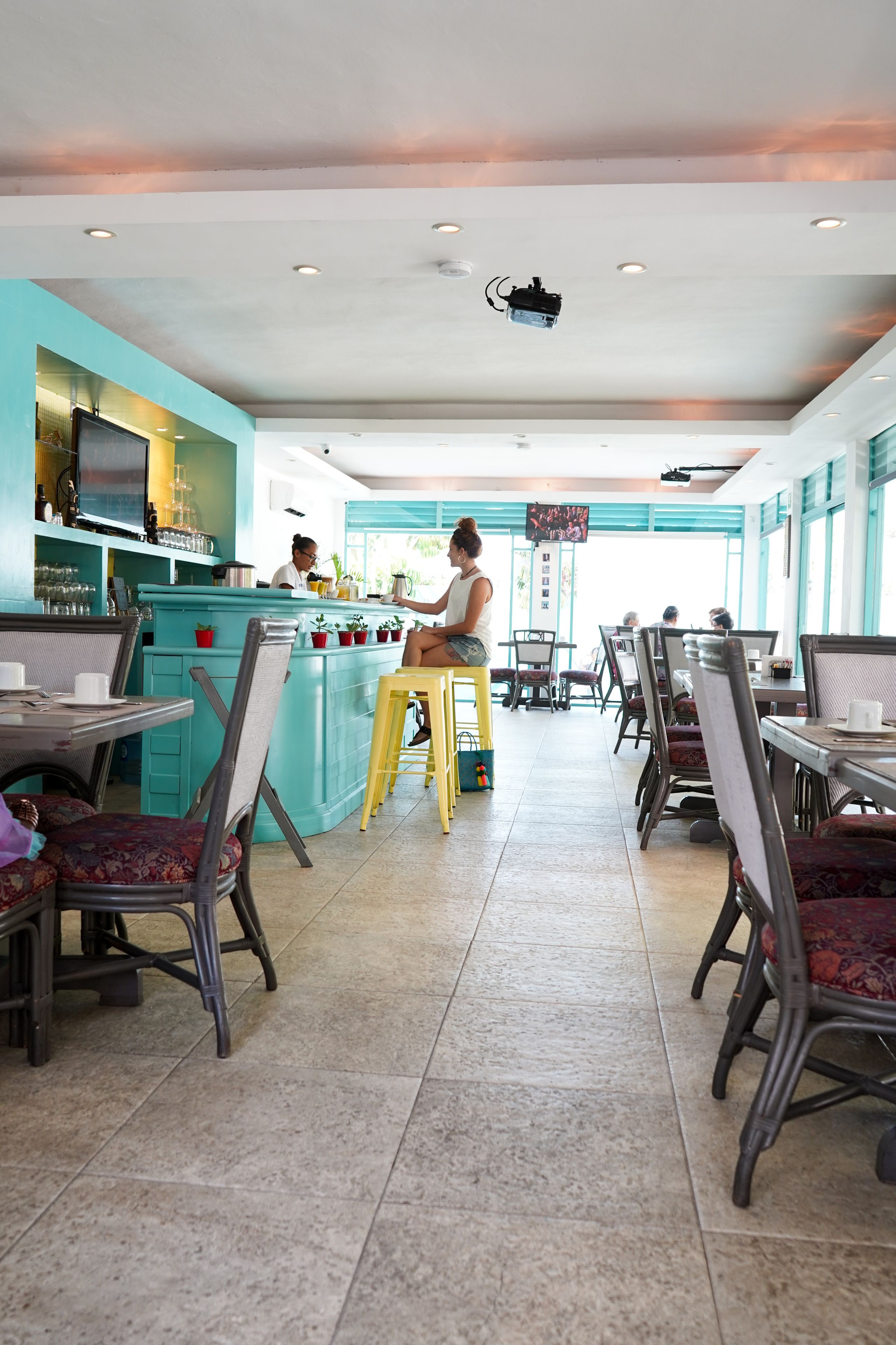 A restaurant with a teal-colored counter, multiple seating areas, and a tiled floor.
