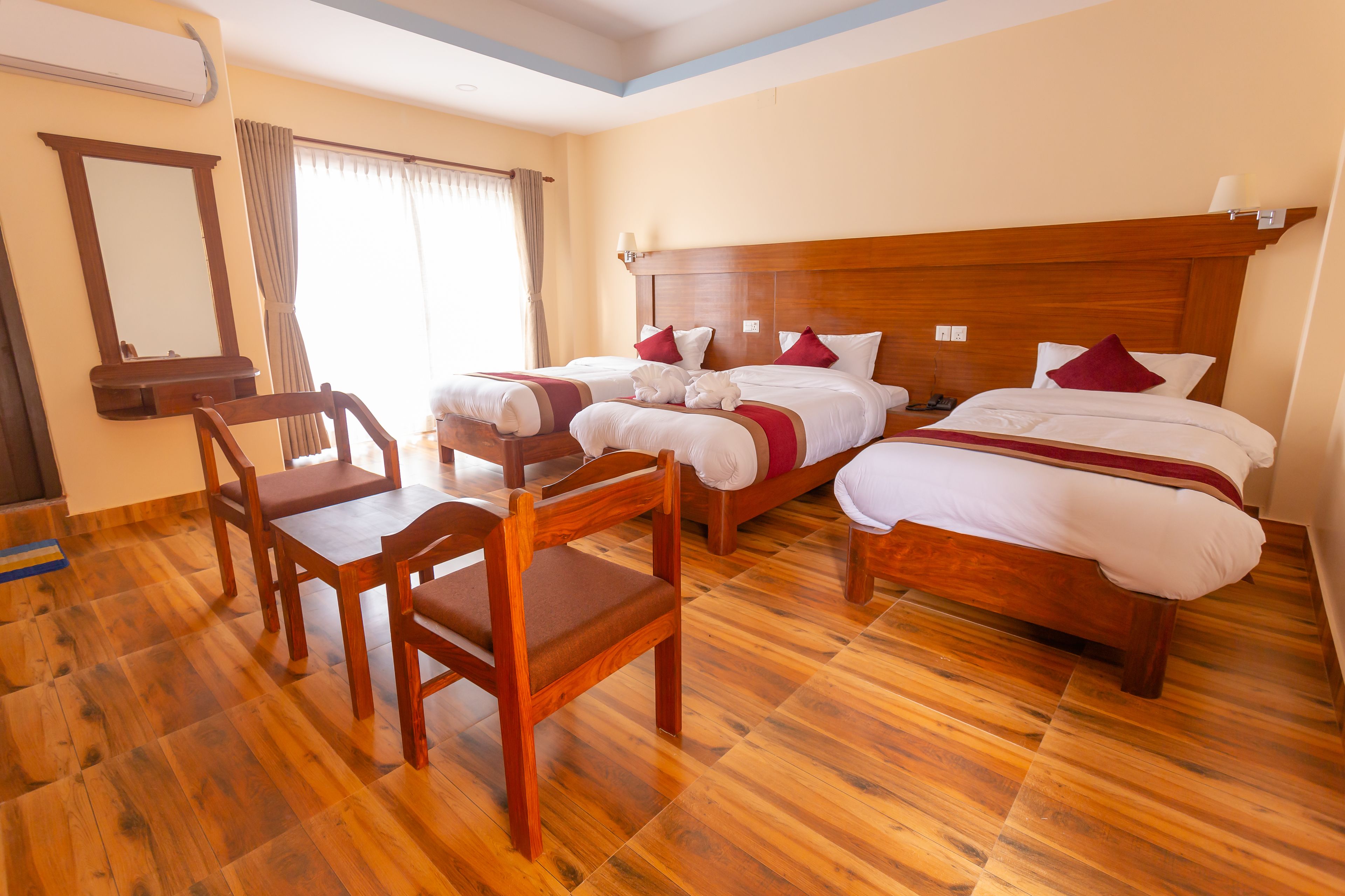A hotel room with two beds, a wooden dining table, and chairs.