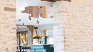 A stone wall interior with a rustic wooden beam ceiling, a teal-colored bar area, and white chairs. - Logis Hôtel-Restaurant Domaine de Montecristo et Gîte l'Évasion Dantès (Bourguignons)