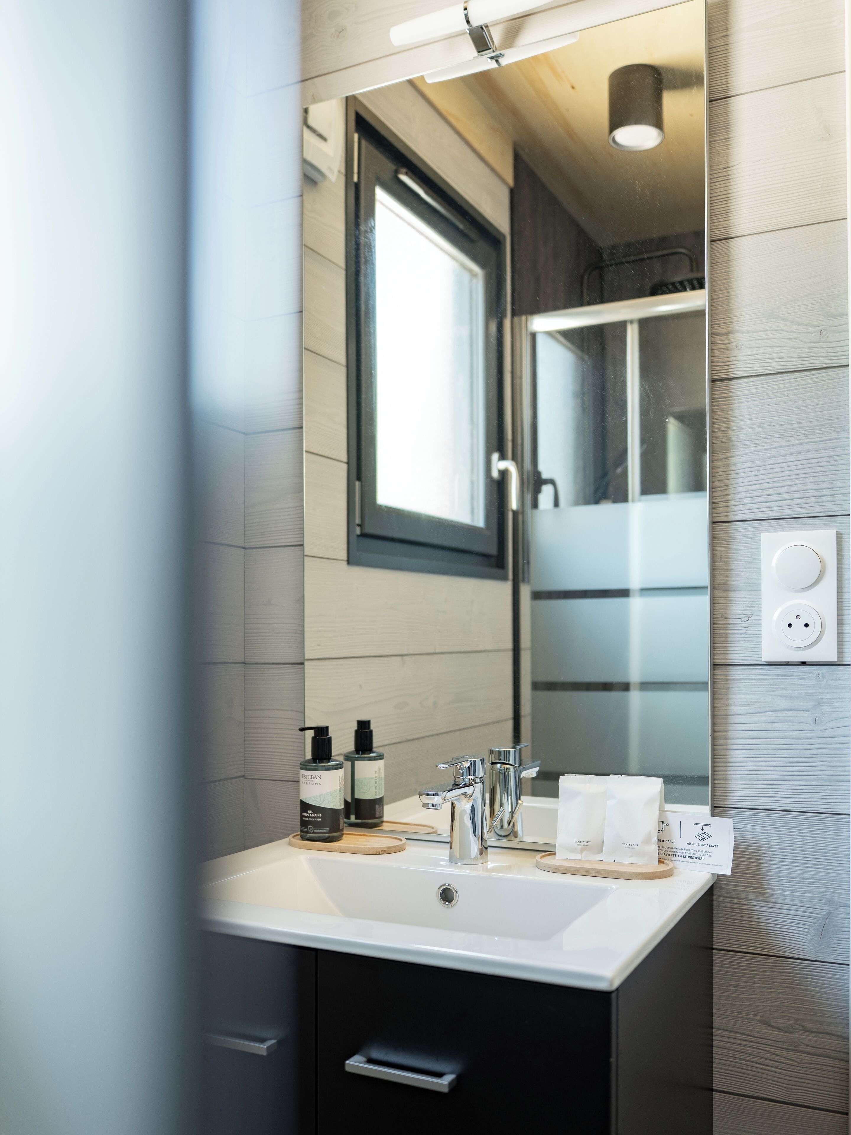 A bathroom with a large mirror, a sink, and two bottles of soap.