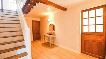A wooden staircase leading to a landing with a wooden door and a small table with a lamp.