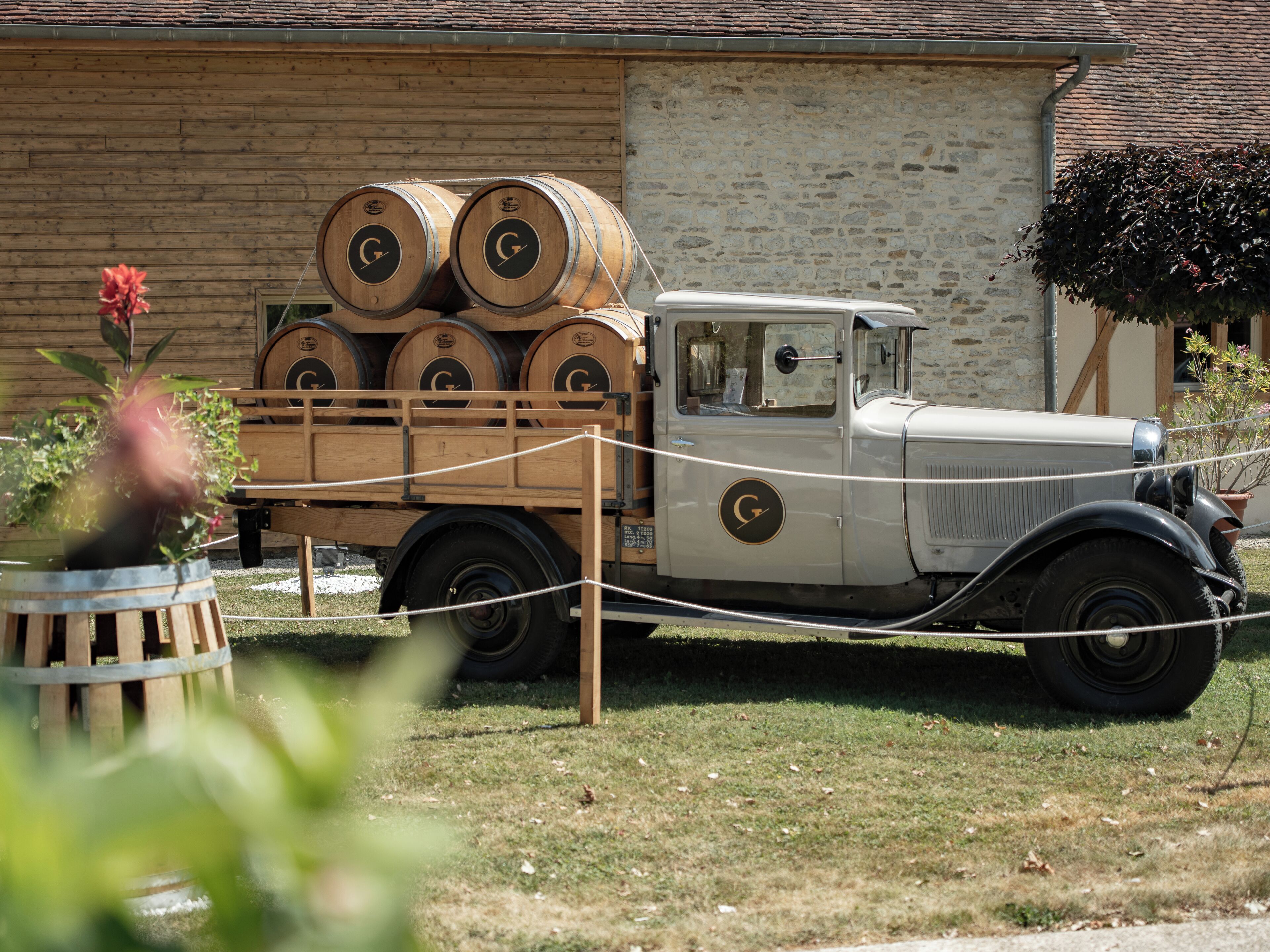 A vintage truck with wooden barrels parked in front of a building.