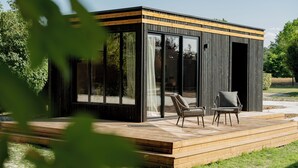 A modern outdoor structure with a deck, two chairs, and a glass door. - Logis Hôtel-Restaurant Domaine de Montecristo et Gîte l'Évasion Dantès (Bourguignons)