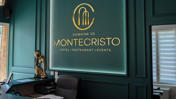 A reception desk with a sign for Domaine de Montecristo hotel, restaurant, and events. - Logis Hôtel-Restaurant Domaine de Montecristo et Gîte l'Évasion Dantès (Bourguignons)