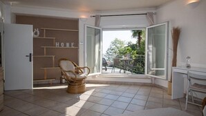 A room with a large sliding glass door leading to a balcony with outdoor furniture and a view of greenery. - Apartment Mia (Opatija)