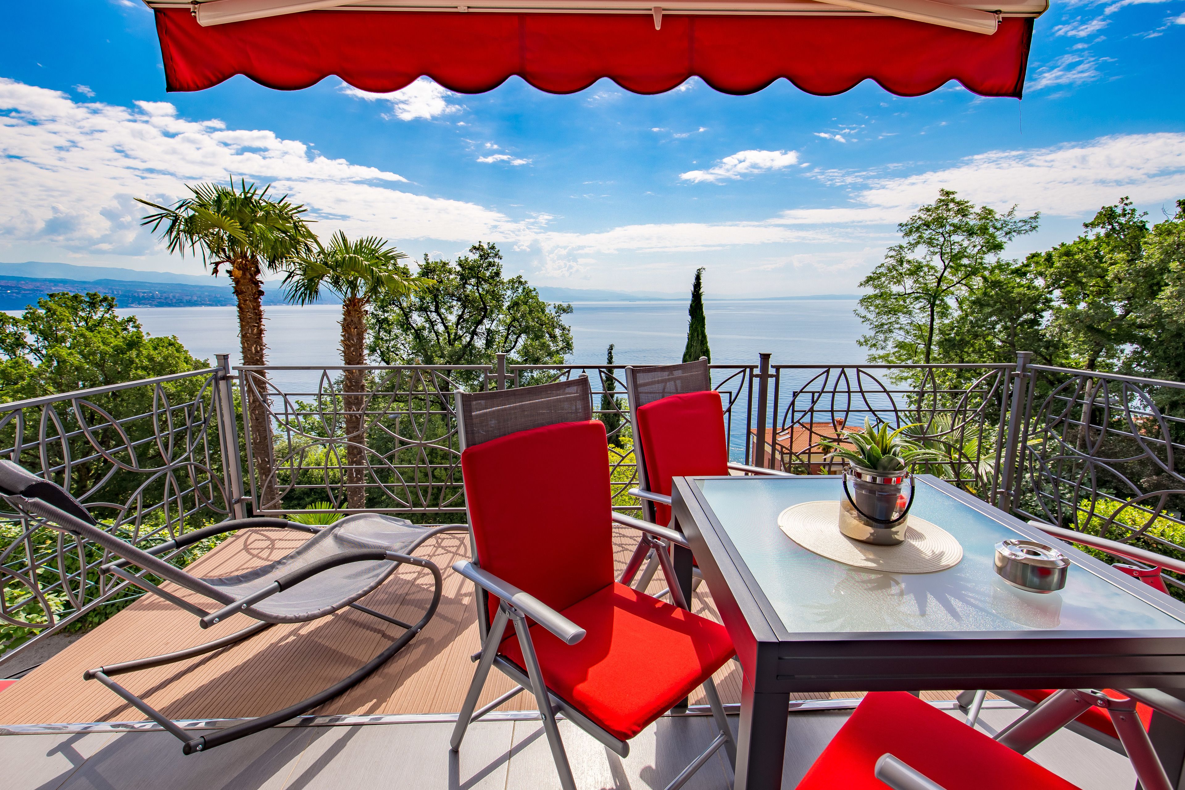 Eine Terrasse mit Tisch und Stühlen mit Blick auf eine malerische Seelandschaft und Berge.