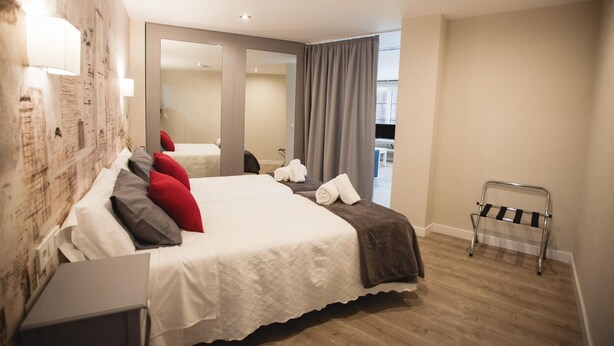 A modern hotel room with a large bed, a mirror, a small table, and a balcony with a view. - LOFT CELINDA CORDOBA ESTACION (Córdoba)
