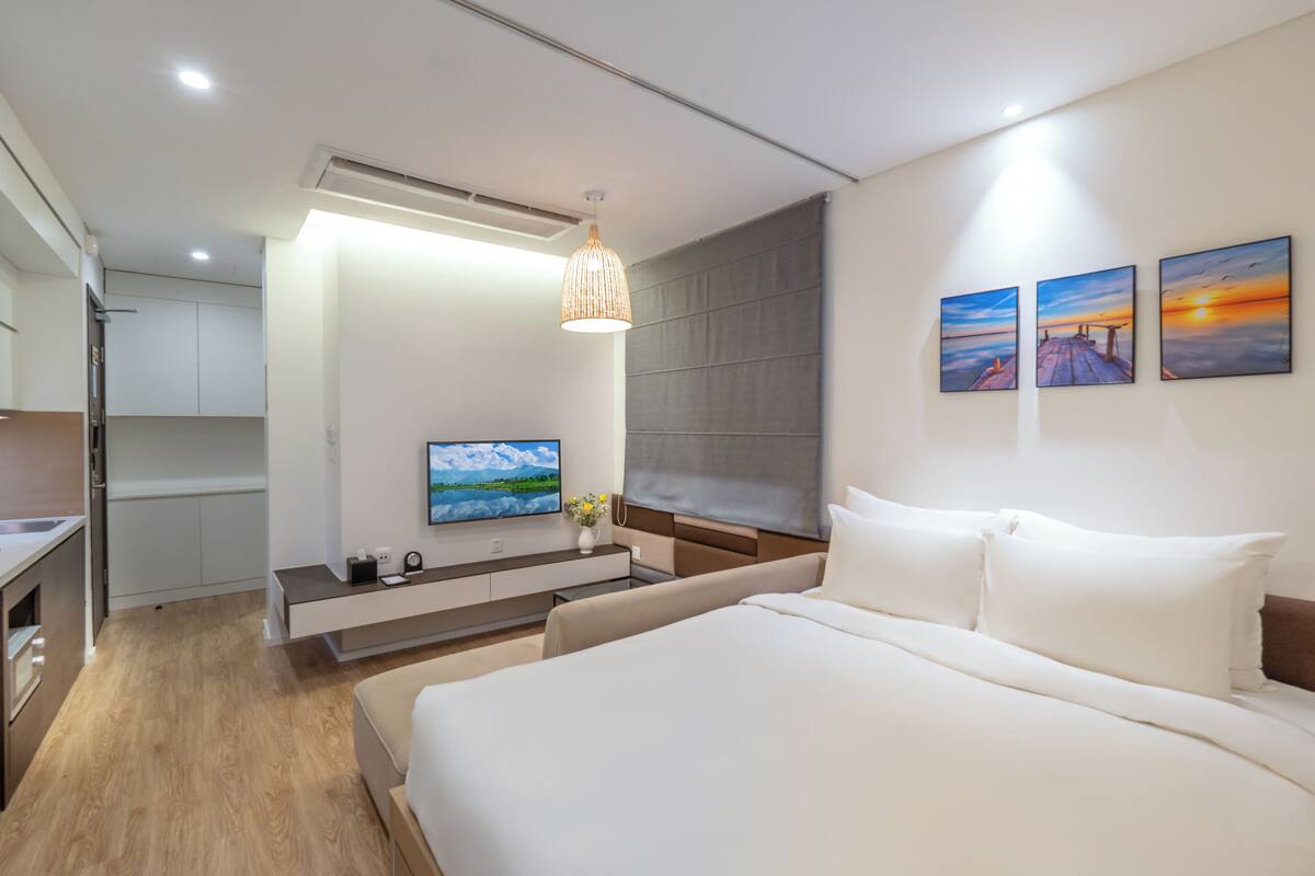 Une chambre d’hôtel moderne dotée d’un grand lit, d’une télévision, d’un bureau et offrant une vue sur la mer.