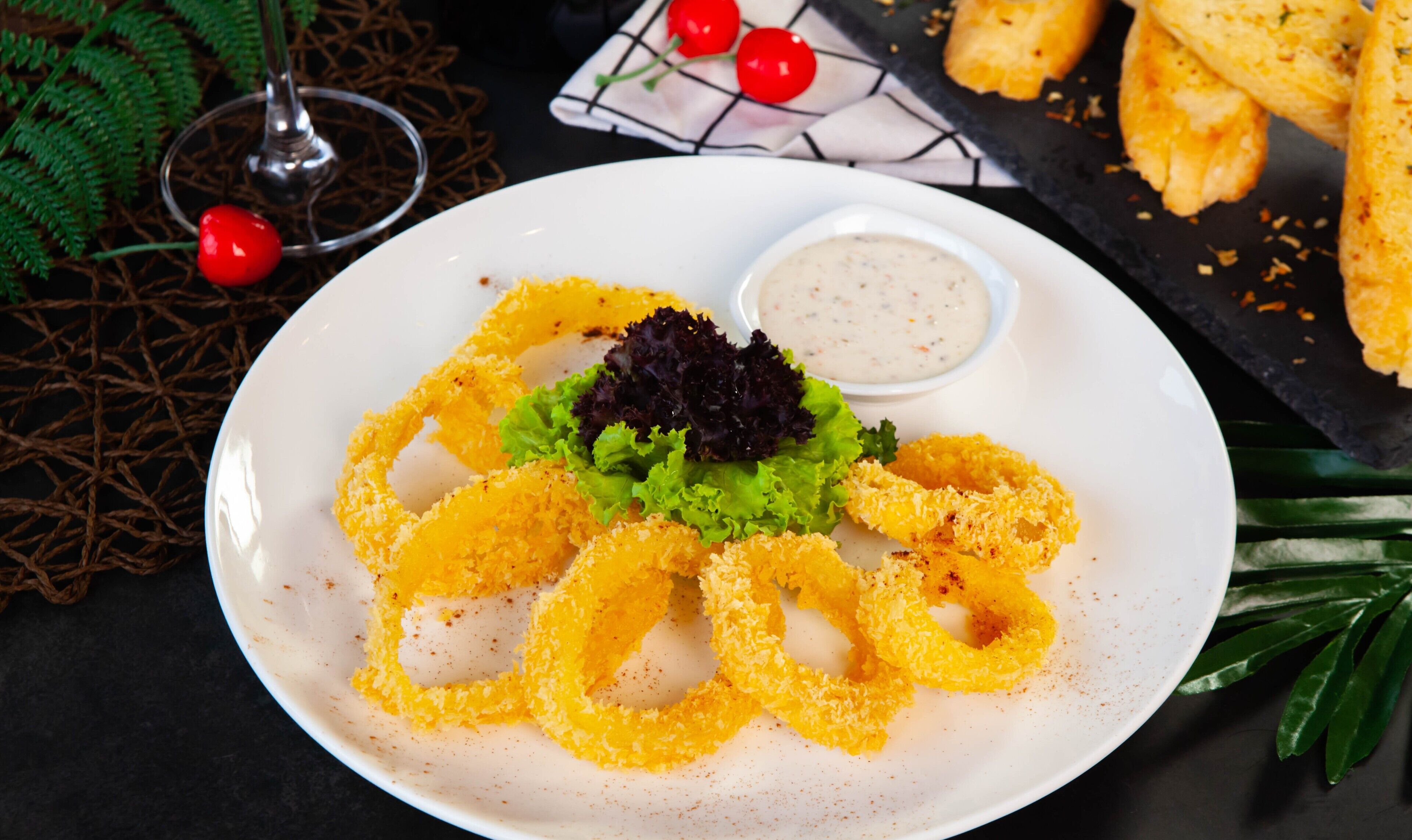 Un plato de calamares fritos acompañado de salsa para mojar y una ensalada pequeña.