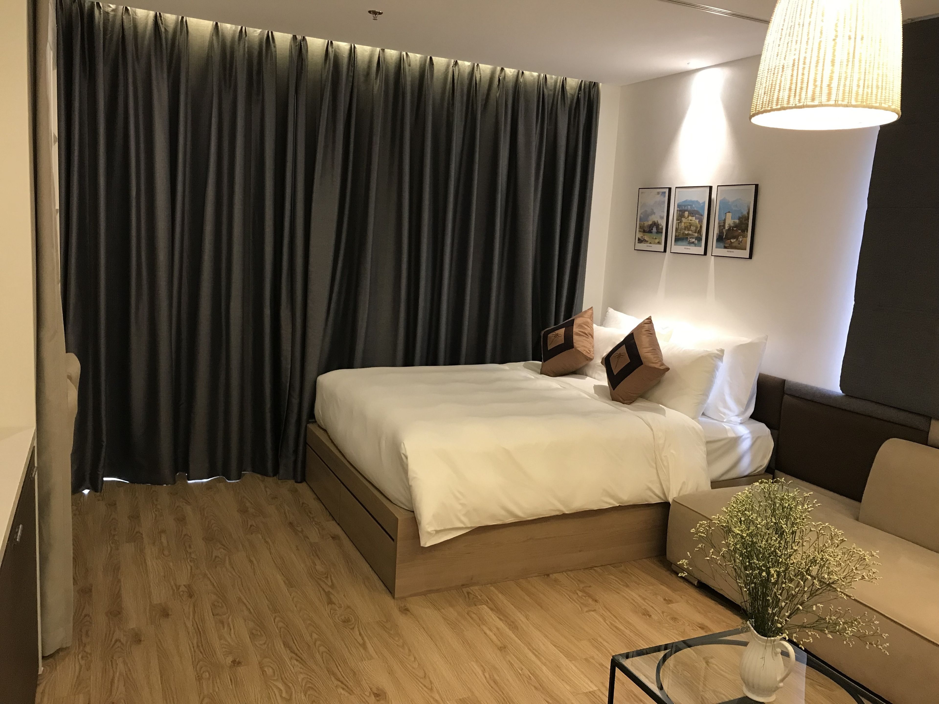 Ein Hotelzimmer mit Bett, Sofa, Blumenvase und Lampe.