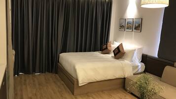 Ein Hotelzimmer mit Bett, Sofa, Blumenvase und Lampe.