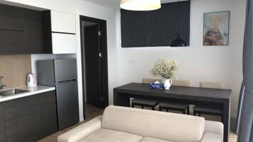 A modern kitchen with dark cabinetry, a white countertop, and a hanging plant.