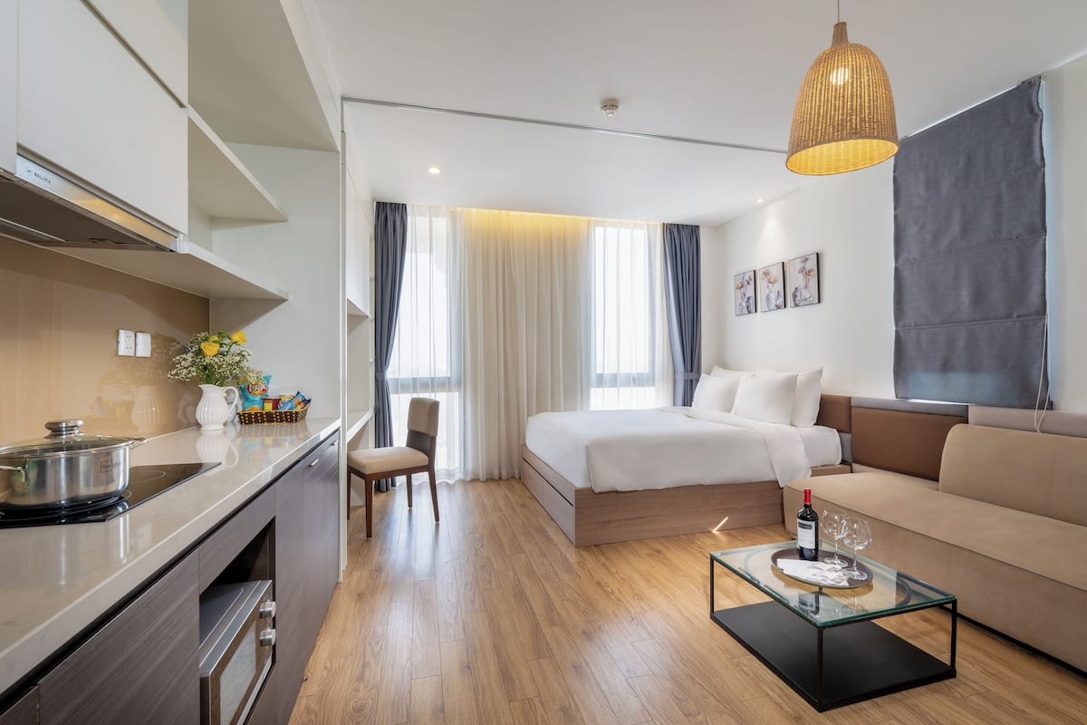Une chambre d’hôtel moderne équipée d’une kitchenette, d’un lit, d’un canapé et d’une table basse en verre.